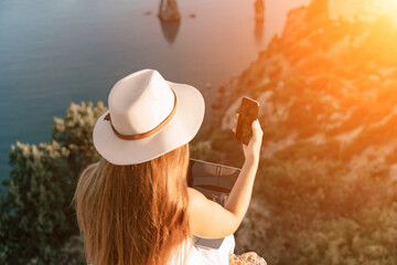 Selfie woman in a hat, white tank top, and shorts captures a selfie shot with her mobile phone...