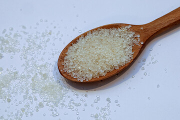 white crystal sugar on wooden spoon close up.