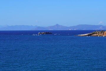Beautiful view of boats, the sea, an island and the coast at Kavouri, in Vouliagmeni, Attica, Greece. The island of Aegina in the background