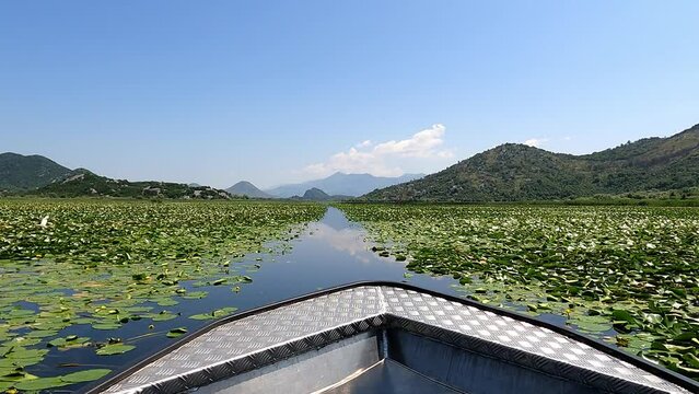 Boat ride on the Rijeka Crnojevića river, Montenegro. Tranquil lake with mountain reflection in rural countryside landscape.