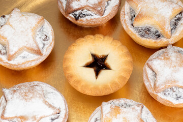 A photograph of Christmas mince pies that are arranged on a gold-colored plate. These traditional treats are a favorite over the festive season.