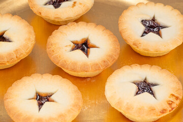 A close-up view of Christmas mince pies arranged on a gold-colored plate. The treats are traditionally eaten at Christmas.