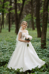 Fototapeta na wymiar young girl bride in a white dress in a spring forest