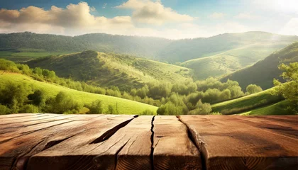 Fotobehang Wooden table set against a backdrop of blurred green hills, cloudy sky, and sunlight © Tatiana