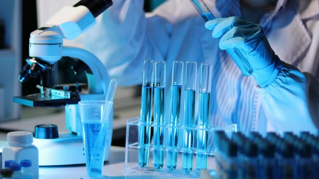 Doctor scientist analyzes a colored liquid to extract the DNA and molecules in the test tubes in the laboratory.