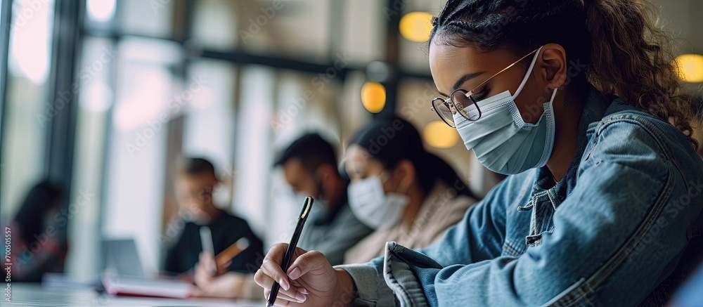 Poster Group of diverse international students wearing protective masks and talking discussing project sitting at desk in the classroom at the university. Creative Banner. Copyspace image