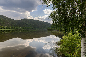 Tranquil scene from a riverbank, peering through birch branches over Norway's serene Glomma River