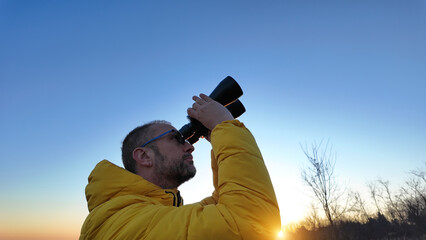 Amateur astronomer observing skies with binoculars.