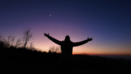 Man with arms wide open enjoying outdoors under stars, planets and Moon..