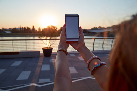 Woman holding cellphone outdoors in sunset time. - Powered by Adobe