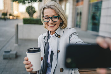 One mature woman outdoors take photos or video call with mobile phone