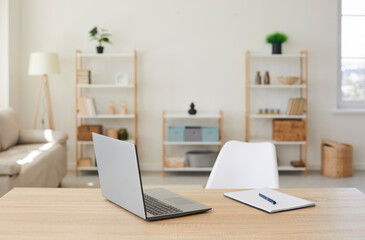 Close up of empty working place of wooden desk with laptop computer and notepad for a business man or a student. Freelancer comfortable home workplace concept. Modern interior of comfortable office.