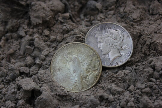 Two 1922 Silver Peace Dollars On Ground in Dirt