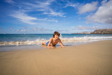 Fototapeta na wymiar Portrait of a teenager lying on the sandy shore of the ocean.