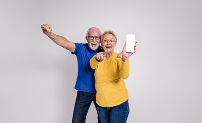 Ecstatic senior couple screaming and showing blank screen of smart phone against white background