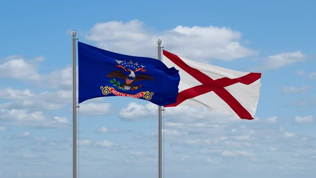 Alabama and North Dakota US state flags waving together on cloudy sky, endless seamless loop
