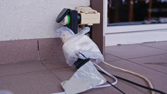 Electric Outlet Plug Extender with Multiple Power Cords Connected and Wrapped in Plastic Bags for Temporary Waterproofing