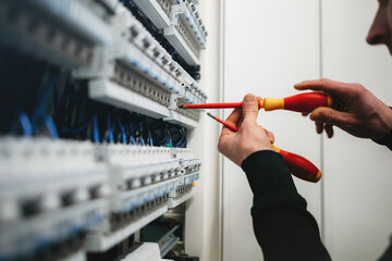 Close up of electrician using screwdrivers in fuse box
