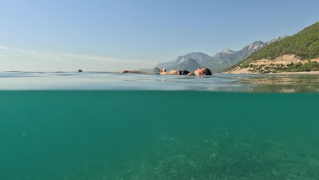 Travel and Holiday concept. Young female on holidays enjoy floating on a crystal clear water beach of Antalya Turkey. Asian beautiful woman swimming with open arms. Relax and tranquility