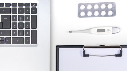 Workplace with laptop, digital thermometer, pills and notebook on white background
