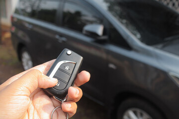 Driver pressing car lock or unlock alarm key and pointing it to his car