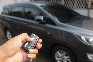 Driver pressing car lock or unlock alarm key and pointing it to his car