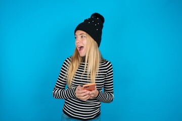 beautiful caucasian teen girl wearing striped sweater holding a smartphone and looking sideways at...