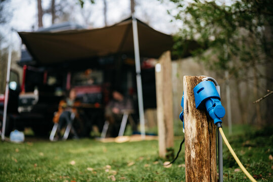 Close up shot of a charging station with blurry people camping in the back