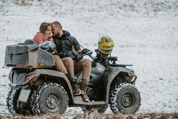 Fototapeta na wymiar A romantic couple shares a tender embrace and kisses while joyously riding a quad through the snowy landscape, creating a magical and passionate moment amidst the wintry adventure