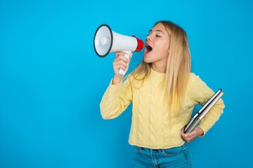 Funny beautiful caucasian teen girl wearing yellow sweater People sincere emotions lifestyle concept. Mock up copy space. Screaming in megaphone.