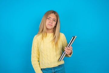 beautiful caucasian teen girl wearing yellow sweater depressed and worry for distress, crying angry...