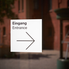 Hinweisschild mit Richtungspfeil für einen Eingang an einem Schaufenster in Berlin