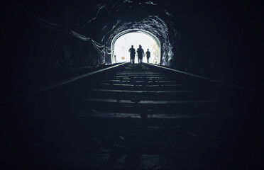 Silhouette of people walking on the railway tunnel in the dark.