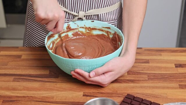 Preparing chocolate dough for the Petit Gateau dessert at home. Young chef mixing dough in a bowl.