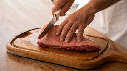 Cook at Traditional Churrasco Brazilian Barbecue. Close up Preparing and cutting raw picanha meat....