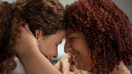 Happy multicultural lesbians are spending a wonderful afternoon in their home embracing and looking...