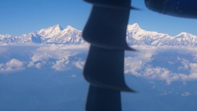 Close up shot of an airplane propeller and mountains in background, zooming out to beautiful blue sky