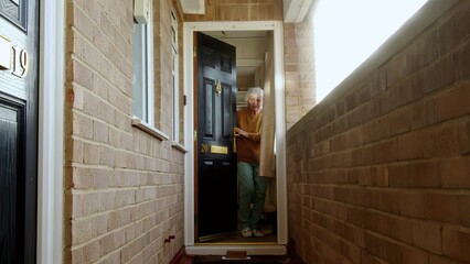 Joyful mature woman receiving cardboard parcel box taking it from floor