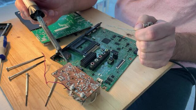 Close up Soldering a micro chip processor with iron tool on a green circuit boad. Electroncs service technology and macro computer concept background.