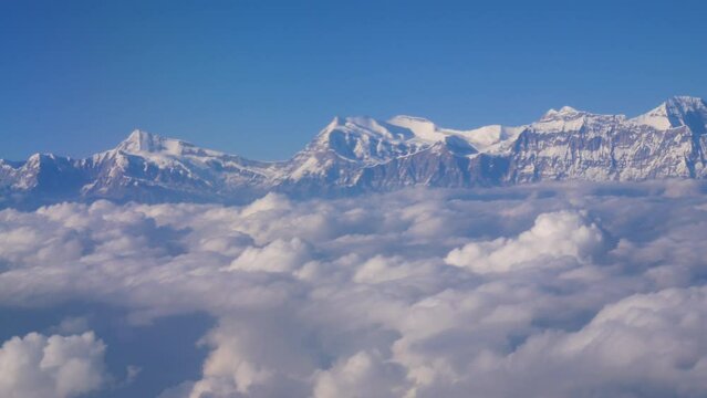 Aerial shot of huge sea of cloud beneath a mountain range, cloudscape full of huge fluffy clouds shot from above