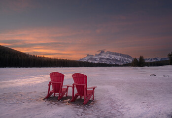 Winter view of a red chairs and Mount Rundle at Two Jack Lake in Banff National Park, Alberta,...