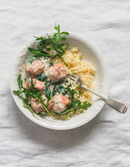 Orzo pasta with salmon meatballs in cream sauce with spinach  lunch on a light background, top view - obrazy, fototapety, plakaty