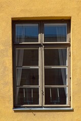 Brown framed window a yellow building.