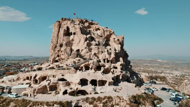 Aerial drone footage of ancient cave town Uchisar in Cappadocia Turkey . Landscape of a city built around huge limestone castle with fairy chimneys on mountain background.