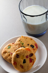 Homemade cookies on a white saucer and a glass of milk.