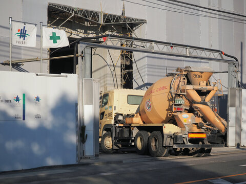 TOKYO, JAPAN - December 29, 2023: A cement mixer truck entering a construction site in Tokyo's Minato Ward.