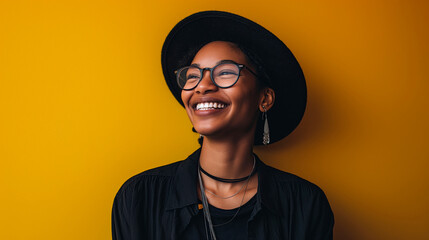 Beautiful young woman, smiling, in hat and black clothes and wearing glasses.