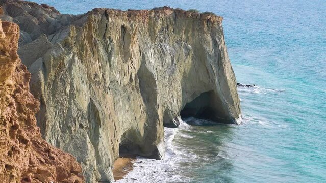 Seascape. Rocky steep coast with grottoes. Island of Hormuz, Strait of Ormuz
