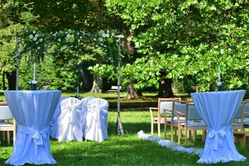Decorated wedding altar at an outdoor wedding in a garden park with white chairs