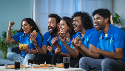 Group of excited Indian cricket fans celebrating by shouting for Team India win in cricket while watching tv at home - concept of cheering supporters, entertainment and championship match - obrazy, fototapety, plakaty